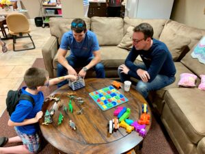 two men and a small boy playing together while sitting around a table