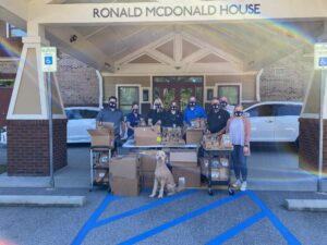 a group of individuals standing in front of the Ronald McDonald House in Columbia, SC showing a donation they have given to the organization.